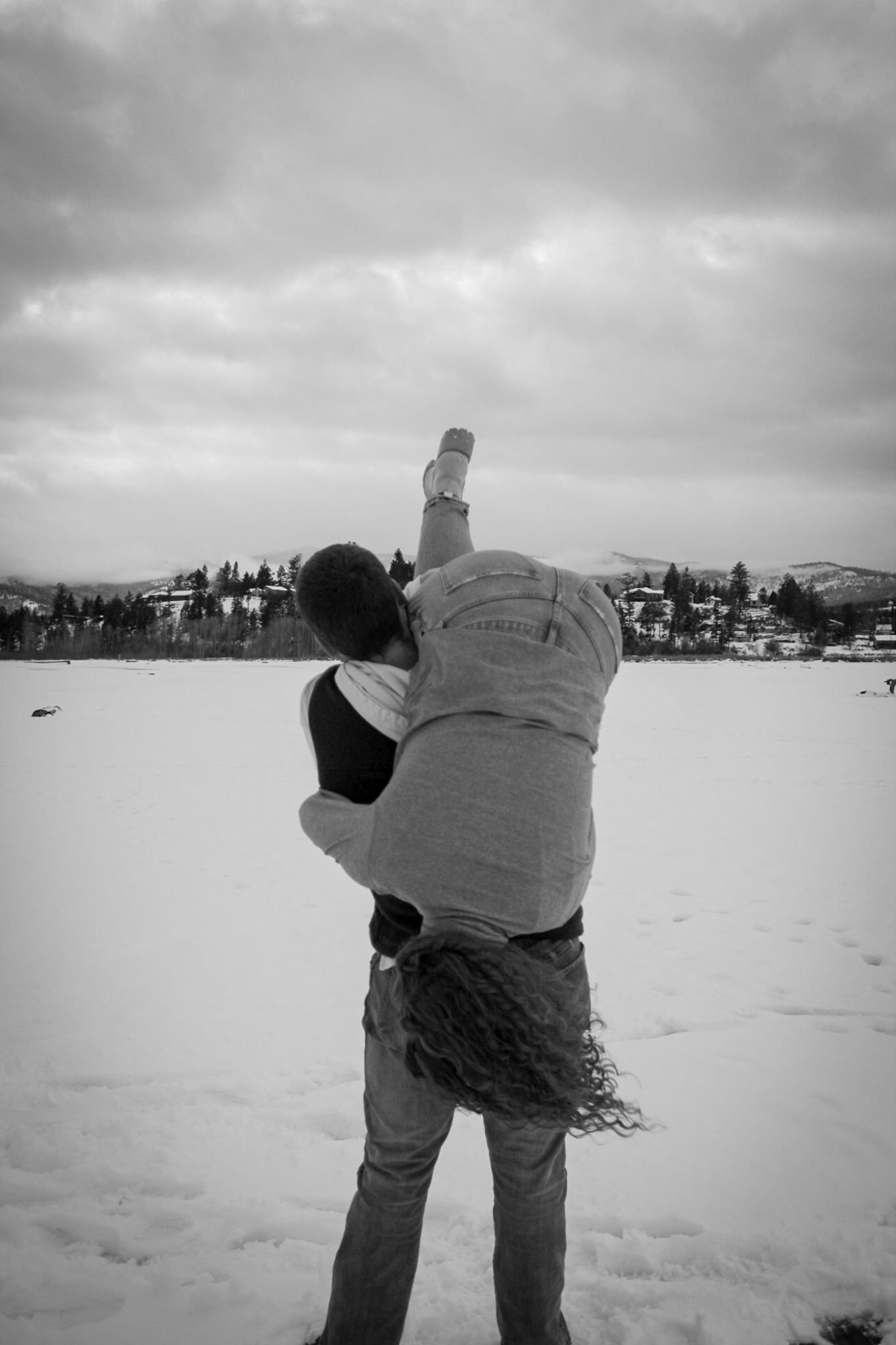 A sequence of black and white photos showing someone ice fishing on a frozen lake with snowy landscapes in the background.