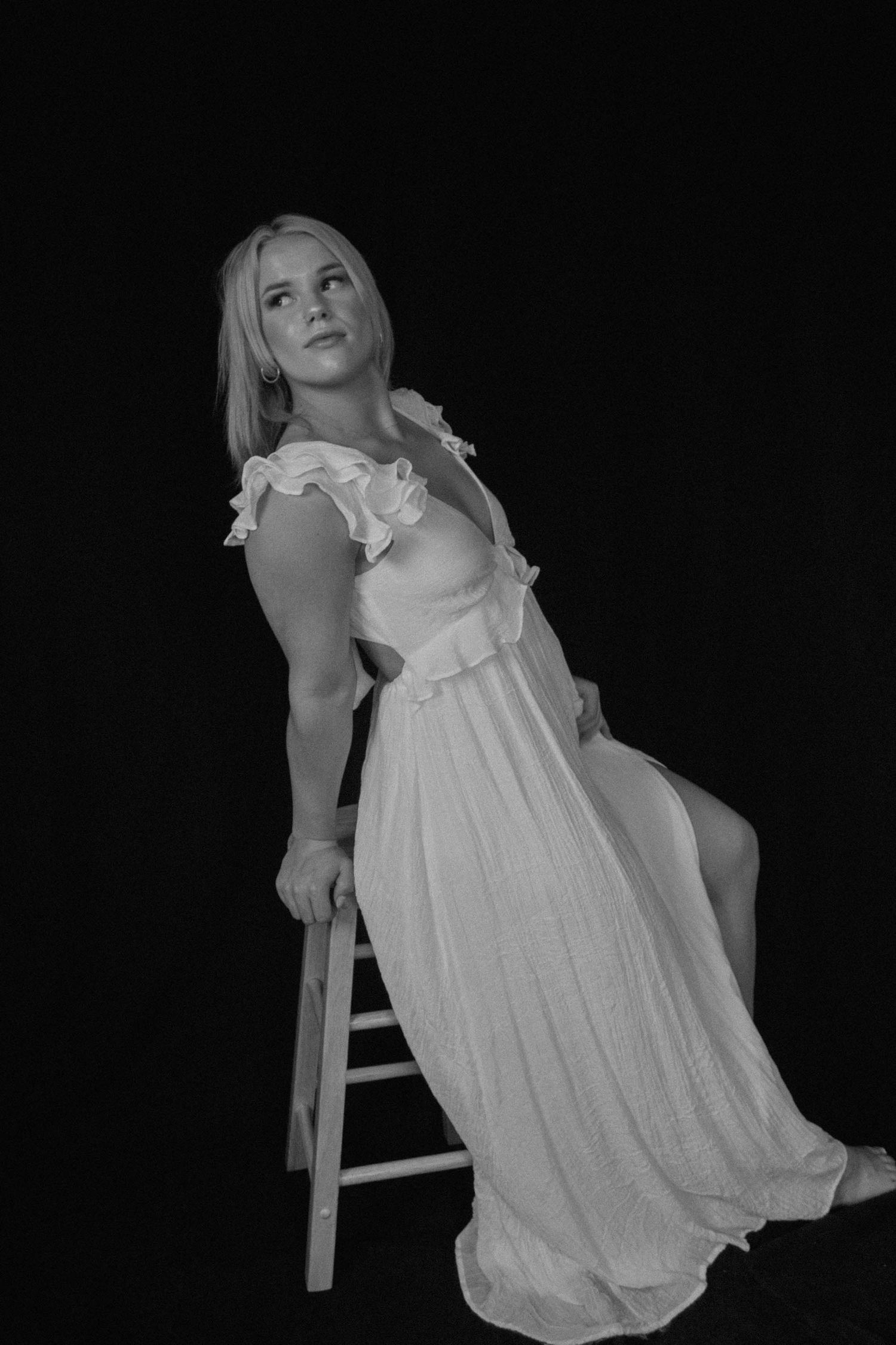 A series of black and white photos showing a person in a white flowing dress posing artistically against a dark background.