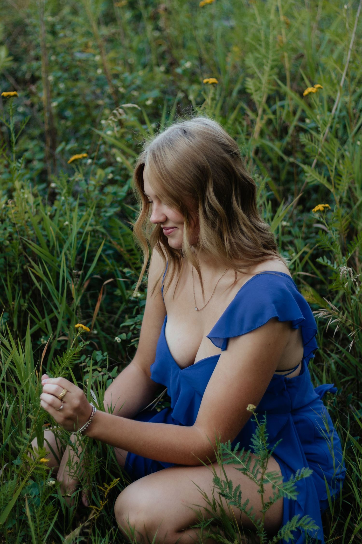 A sequence of artistic portraits in a blue dress among wild summer meadow grasses and flowers.
