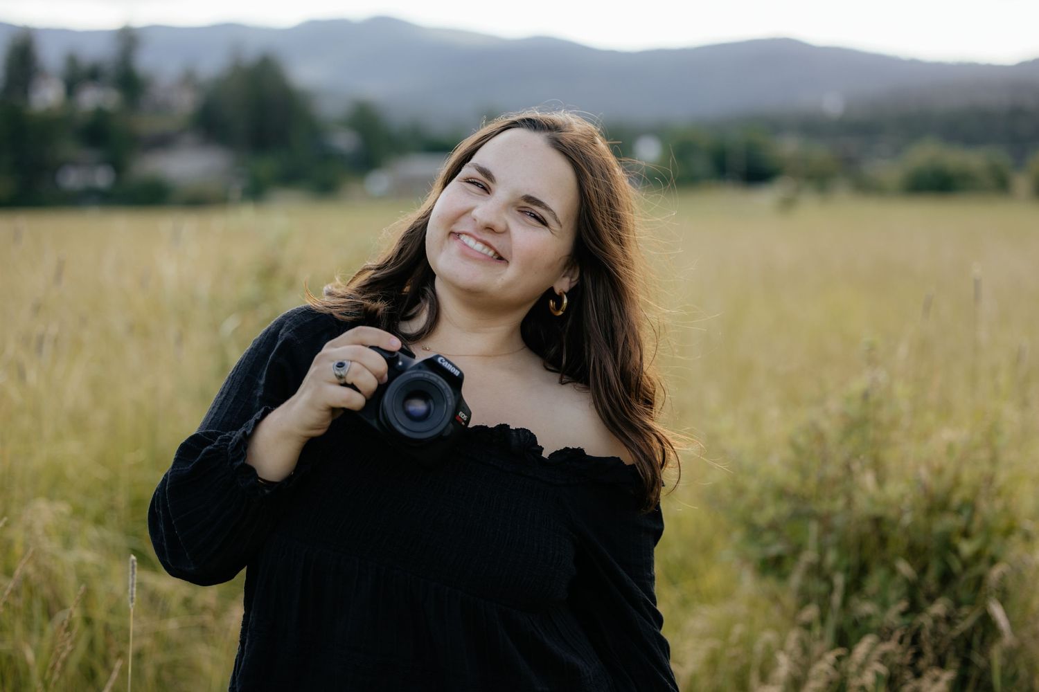 Portrait session in a scenic field with mountains in background.
