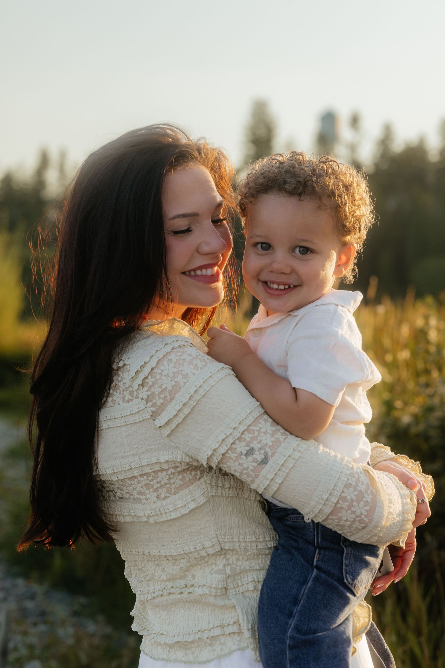 Joyful candid moments of affection and laughter shared between parent and child in warm evening light.