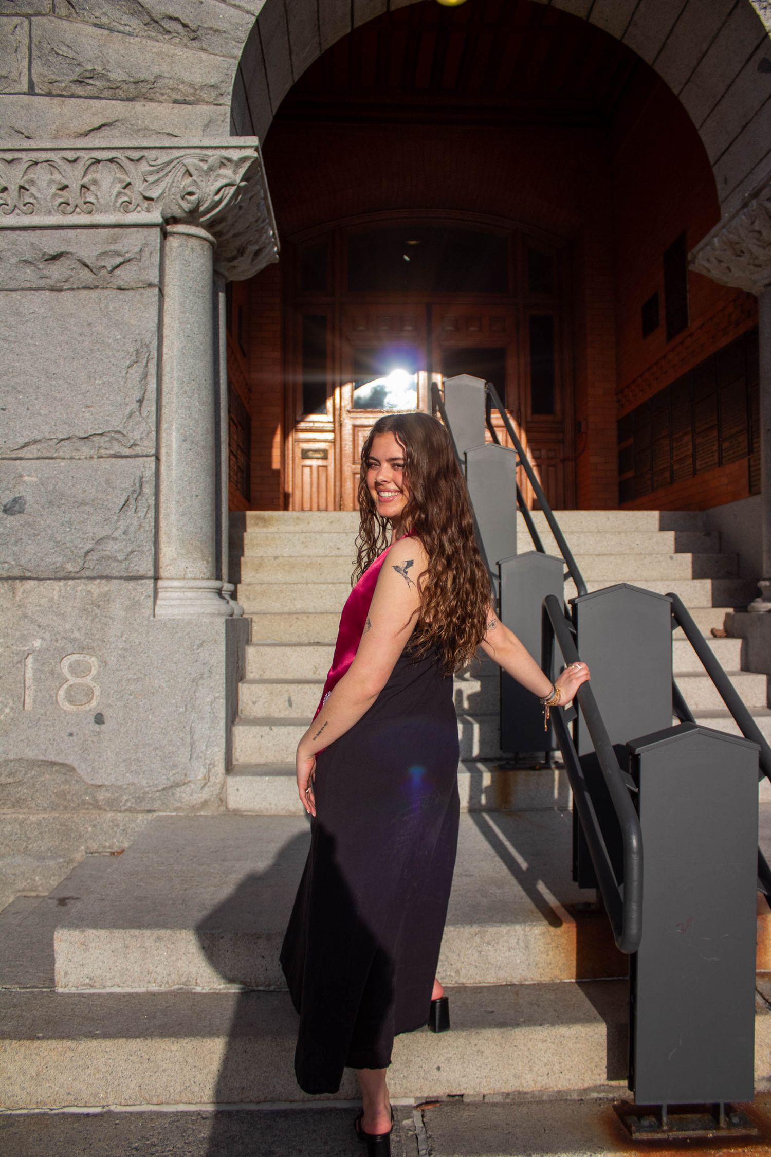 Graduate posing under stone archway in academic regalia.