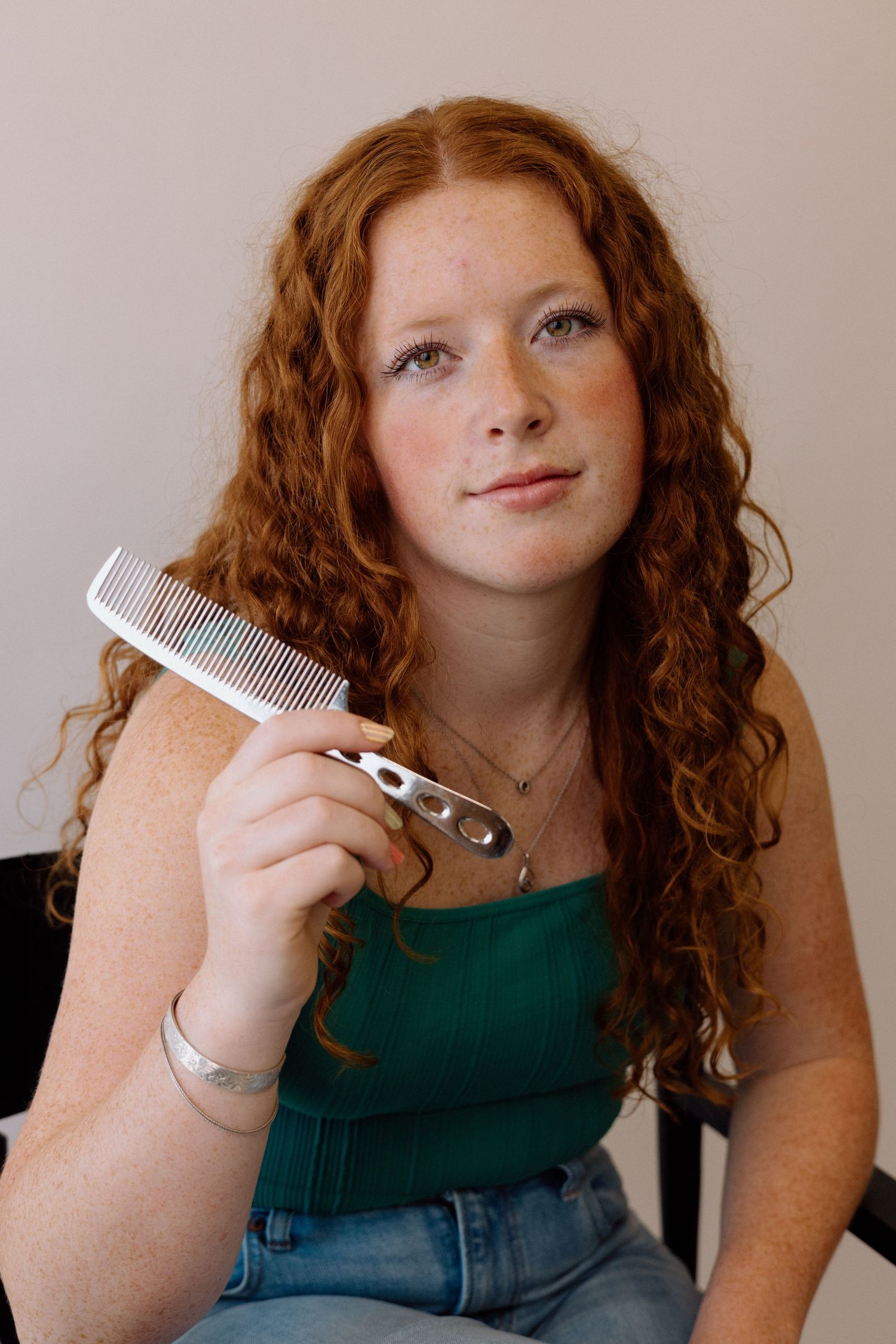 A series of close-up shots showing curly red hair being styled with a white comb against a neutral background.