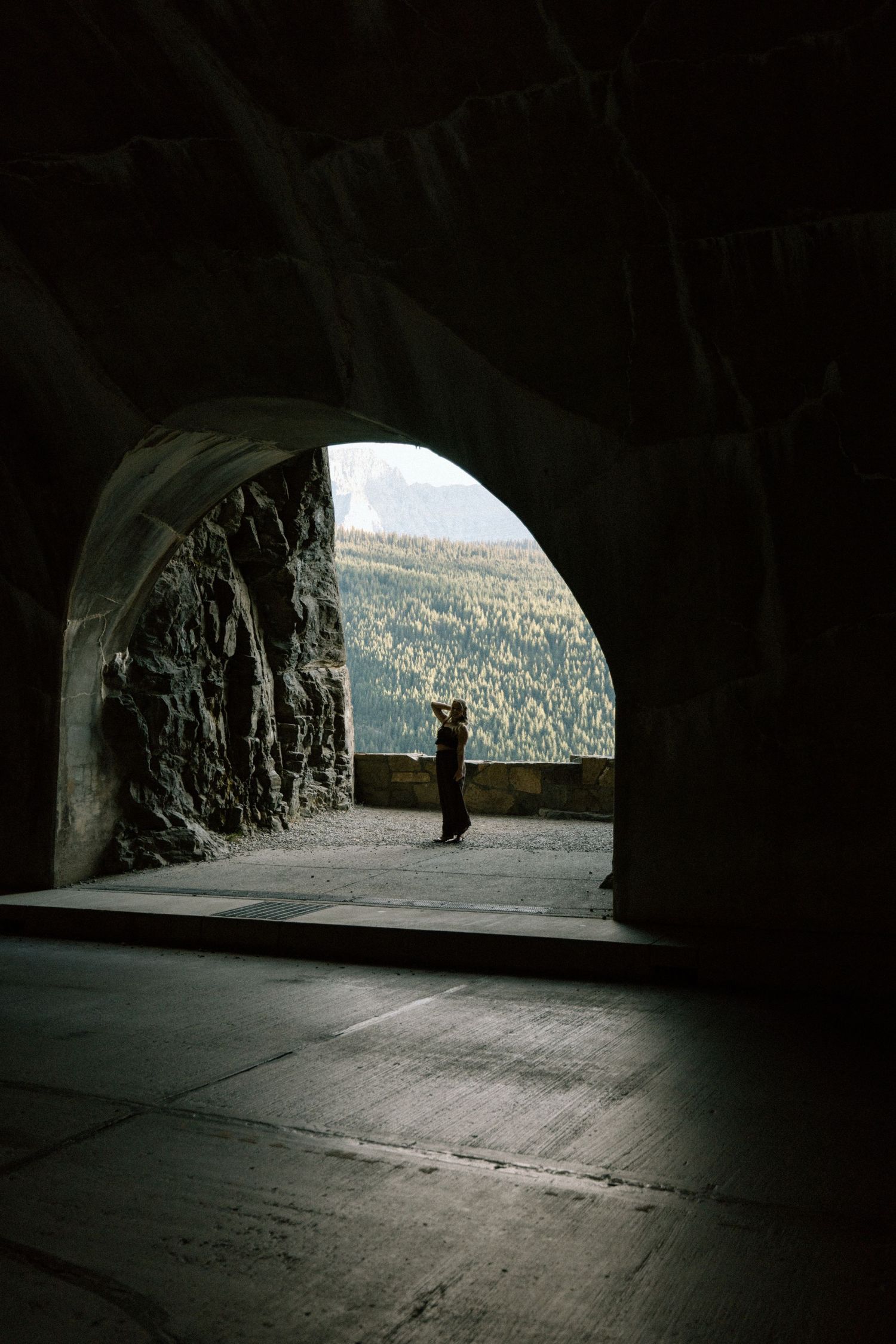 A series of dark tunnel views showing a winding mountain road through carved rock formations with distant landscape visible.