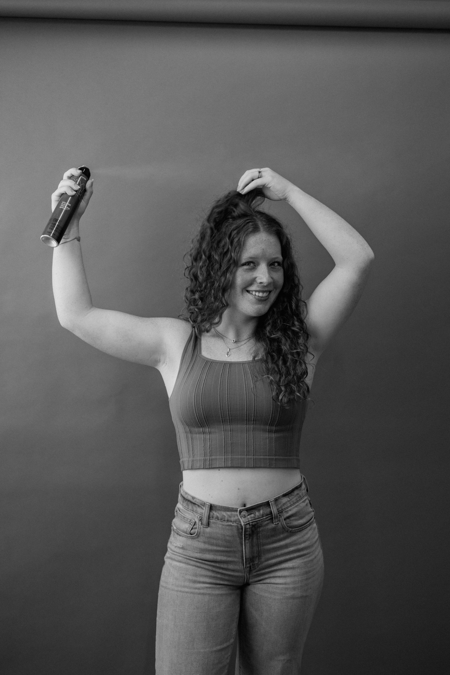 A series of black and white photos showing someone in crop top and jeans posing against a dark background.