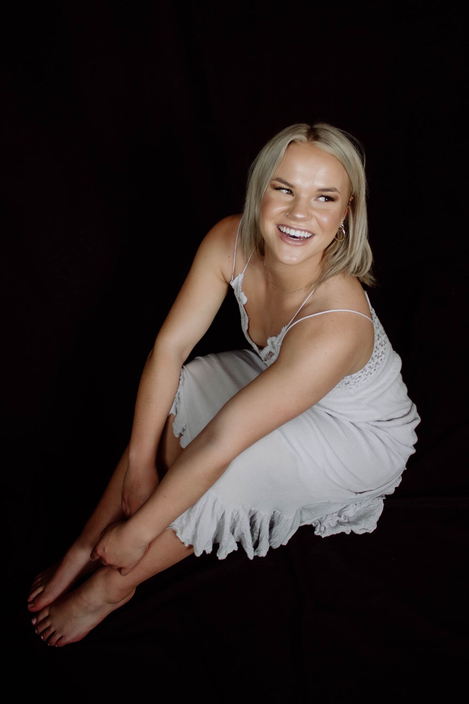 A series of black and white artistic portraits showing a person in white clothing against a dark background.