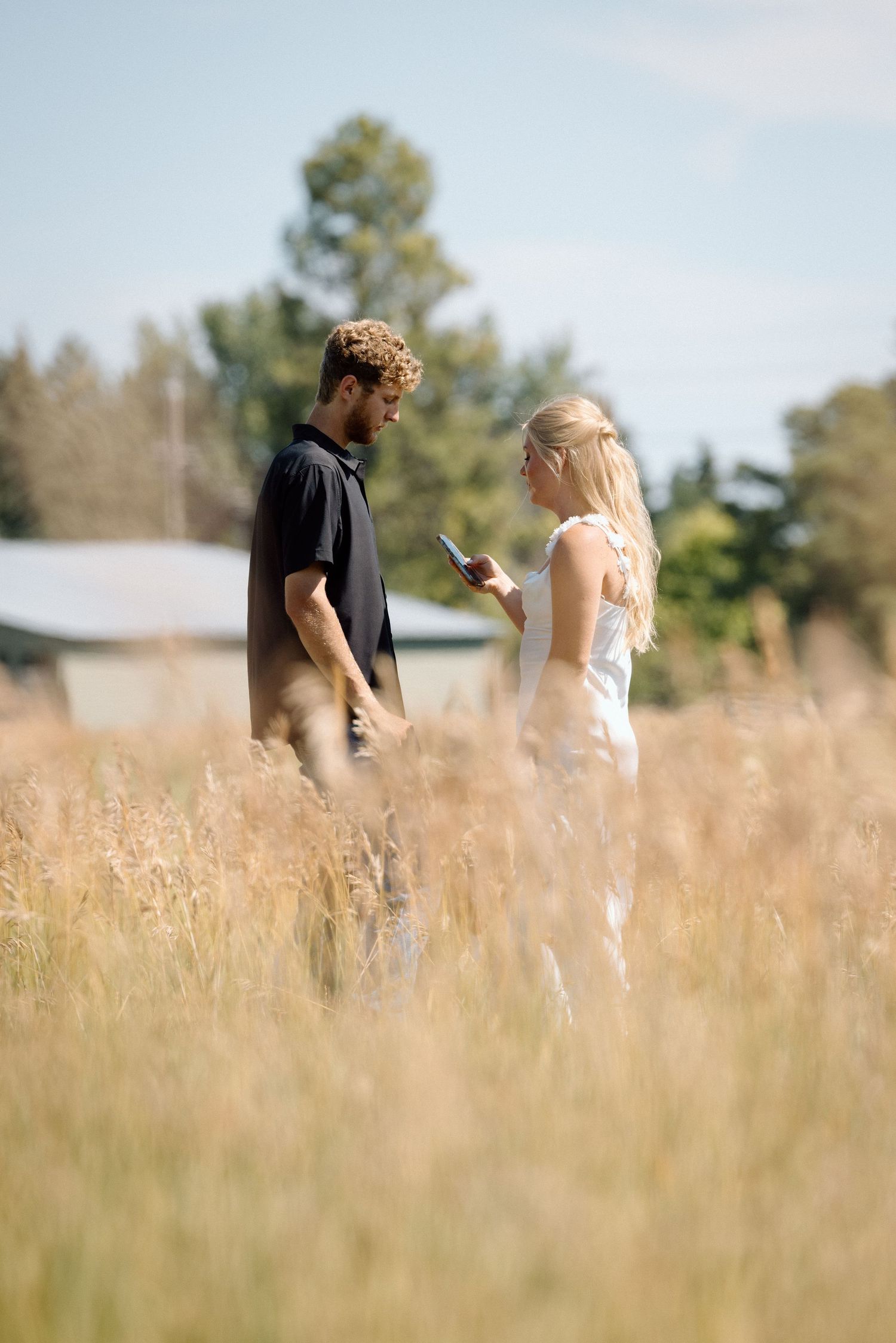 Couple walking through a golden wheat field on a sunny day.