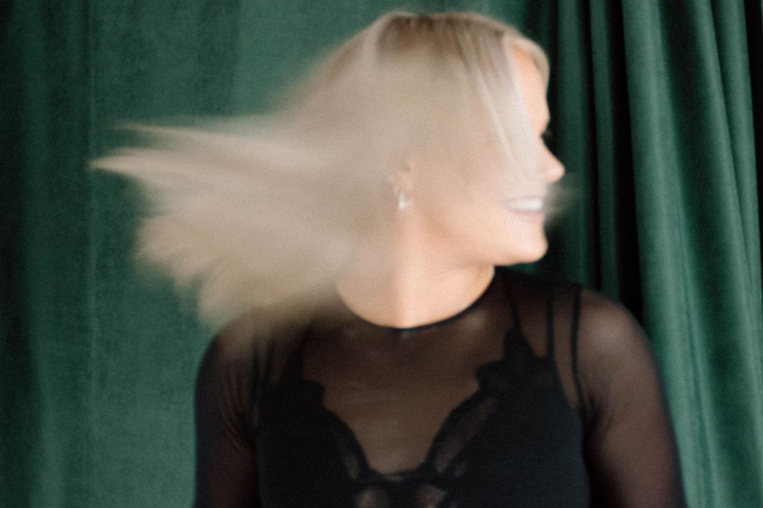 Artistic motion blur portraits against a green curtain background creating ethereal effects in low light.