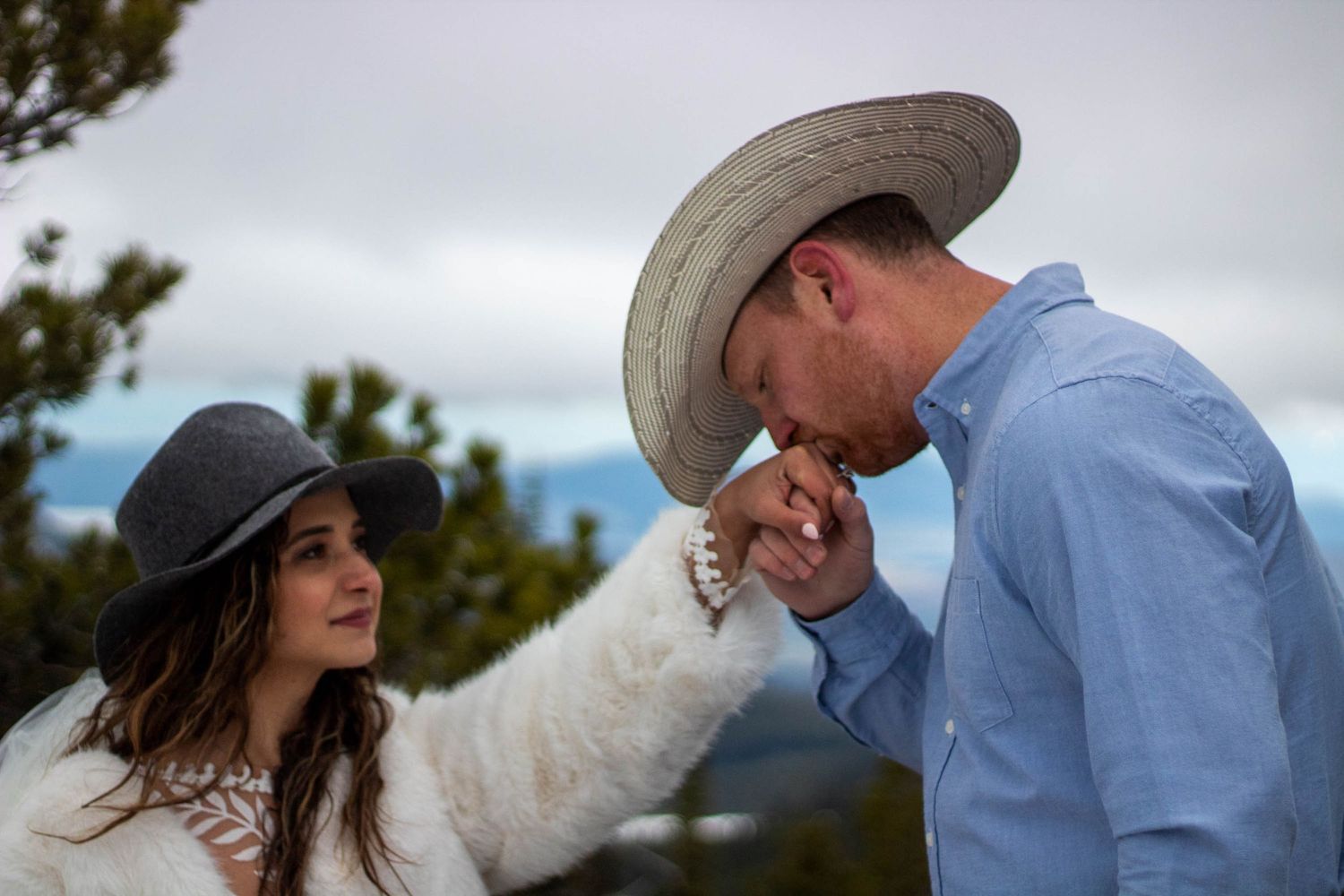 A couple shares a romantic moment together on a cloudy day outdoors.