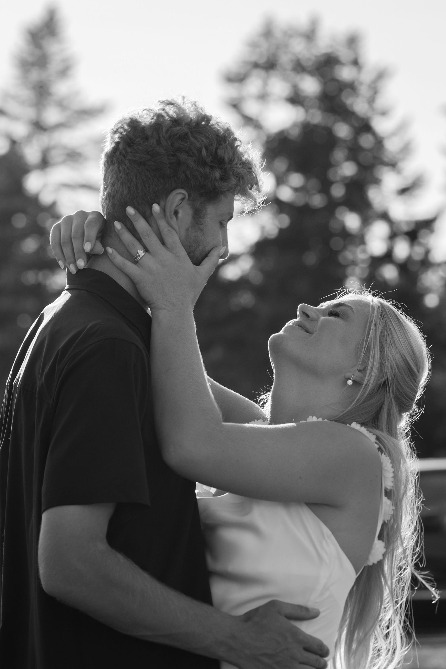 A romantic black and white photo series showing a couple embracing and kissing on a balcony with trees in the background.