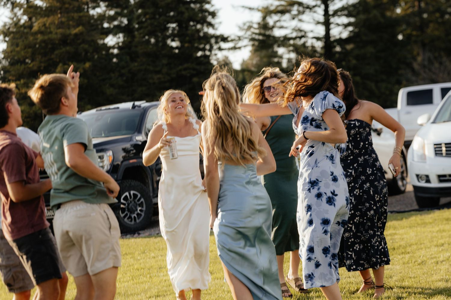 Group of people dancing and celebrating together on a grassy lawn during an outdoor event.
