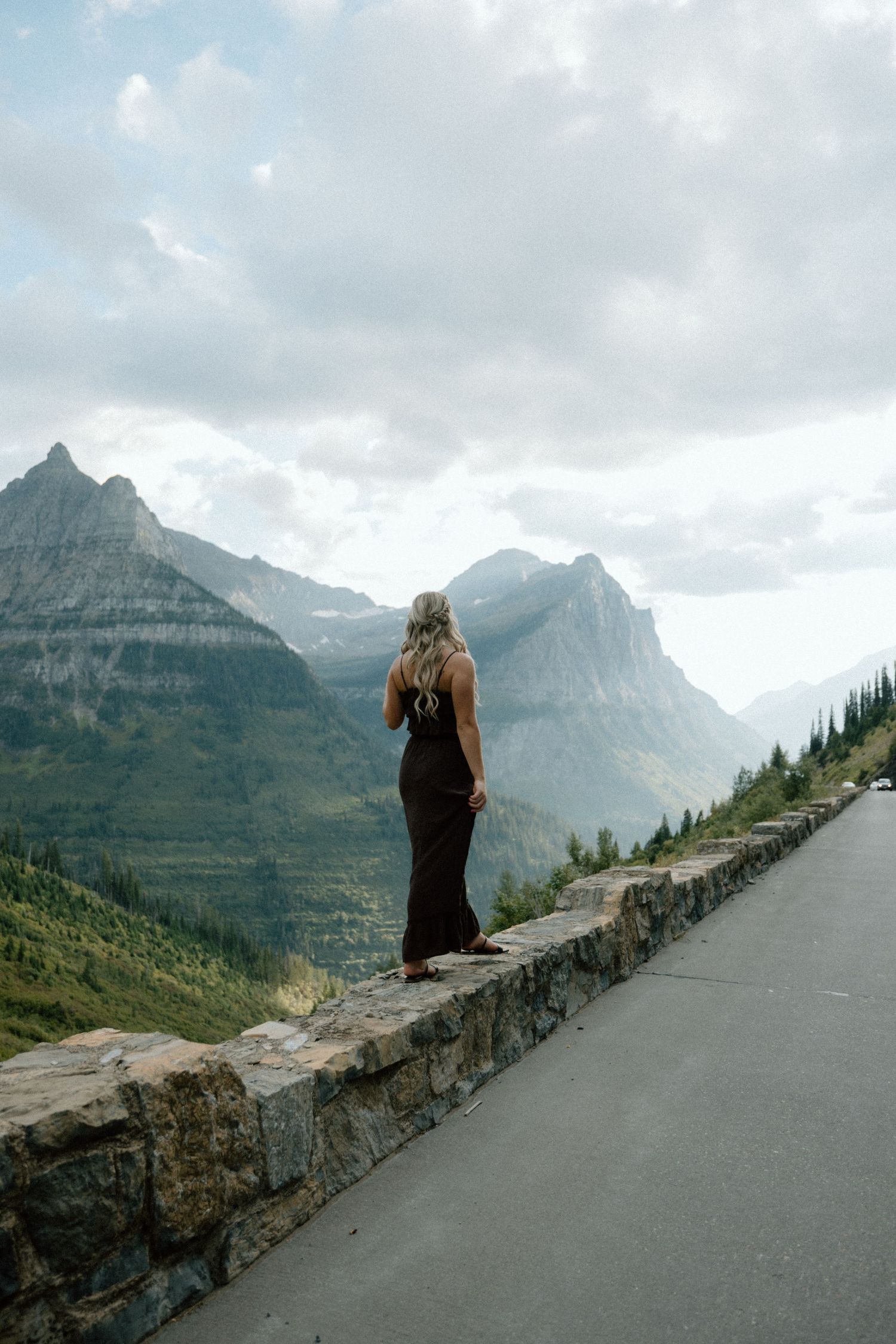 Dramatic mountain vista with stone wall barrier along Going-to-the-Sun Road in Glacier National Park.