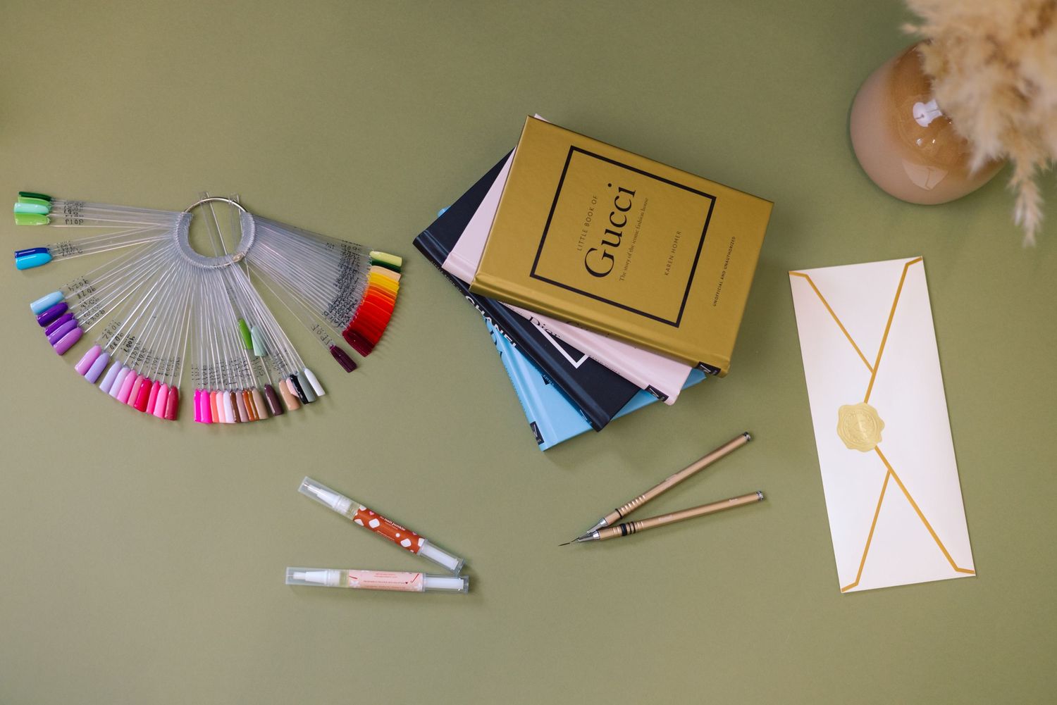 Nail polish color samples, Gucci box, credit cards, and white envelope arranged on a gray surface.