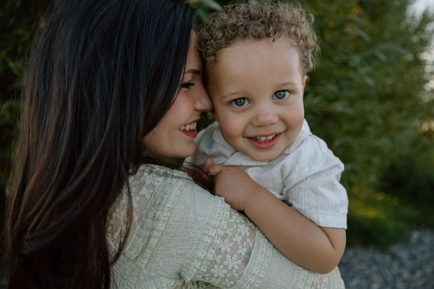 A tender moment between parent and child sharing a joyful embrace outdoors against a green background.