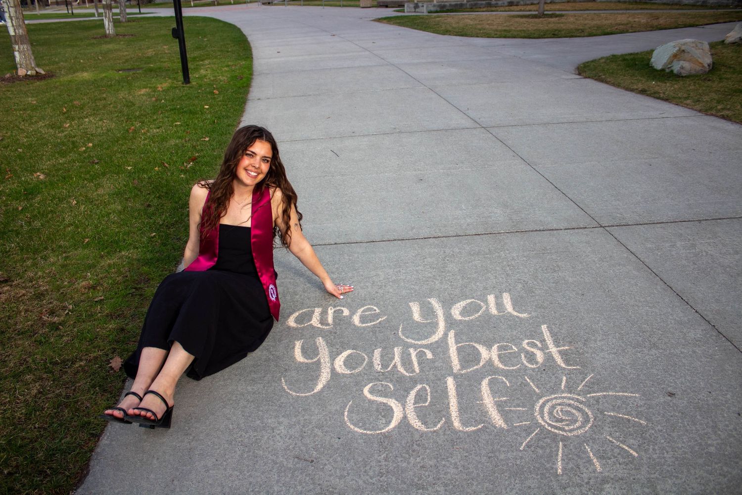 Words written in white chalk on a sidewalk create a romantic message pathway through a park setting in daylight.