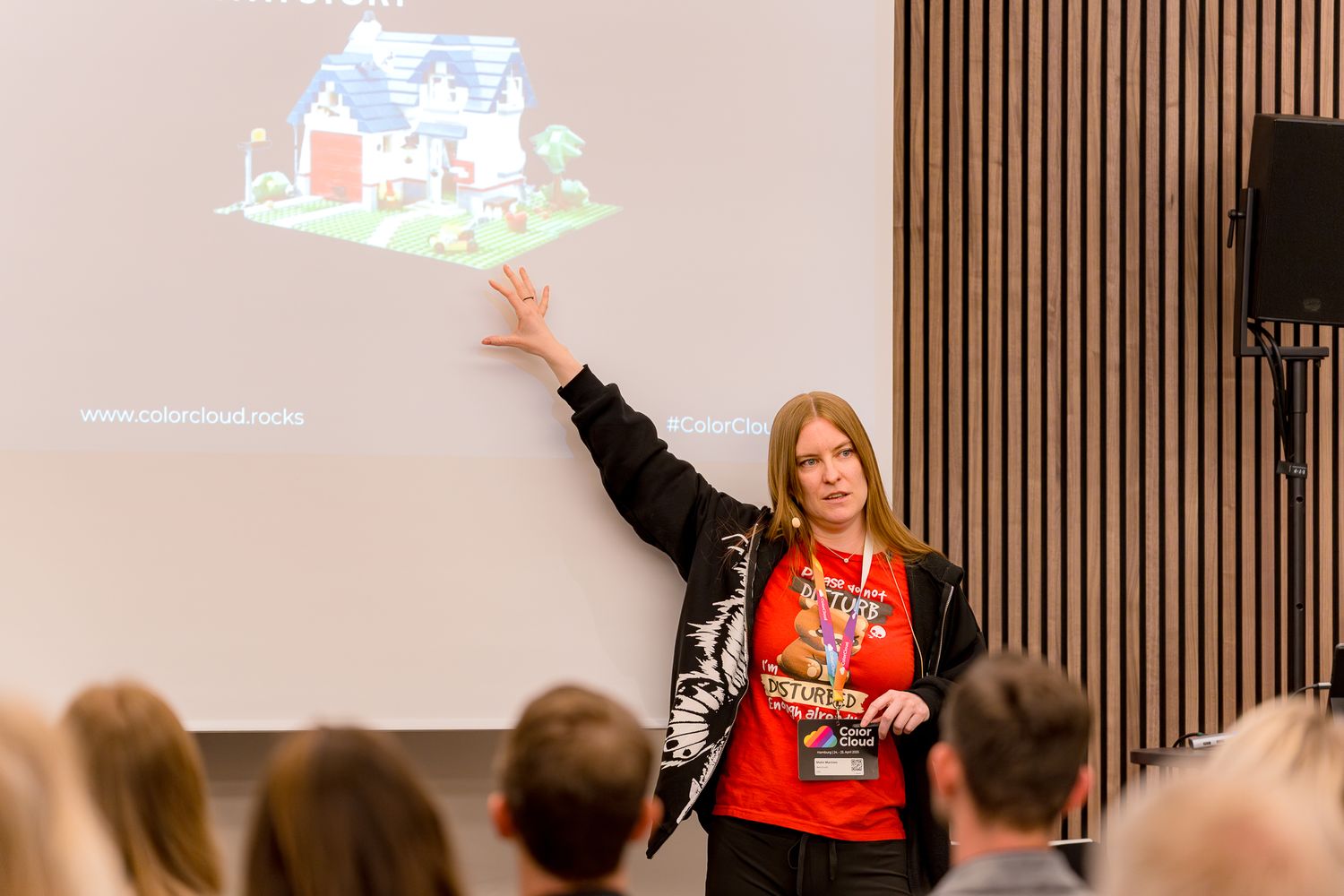 Speakerin Malin Martnes hält auf der ColorCloud 2025 einen Vortrag und zeigt mit einem ausgestreckten Arm auf die Leinwand hinter ihr