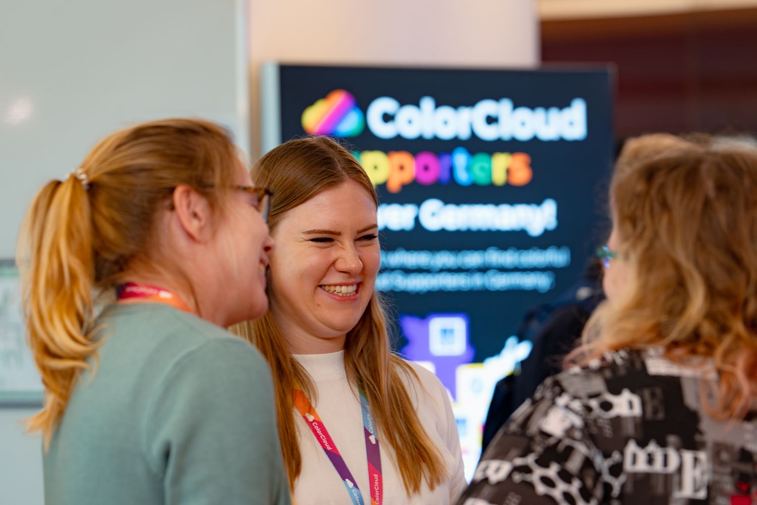 Drei Teilnehmerinnen an der ColorCloud-Konfererenz stehen im Foyer und lachen miteinander