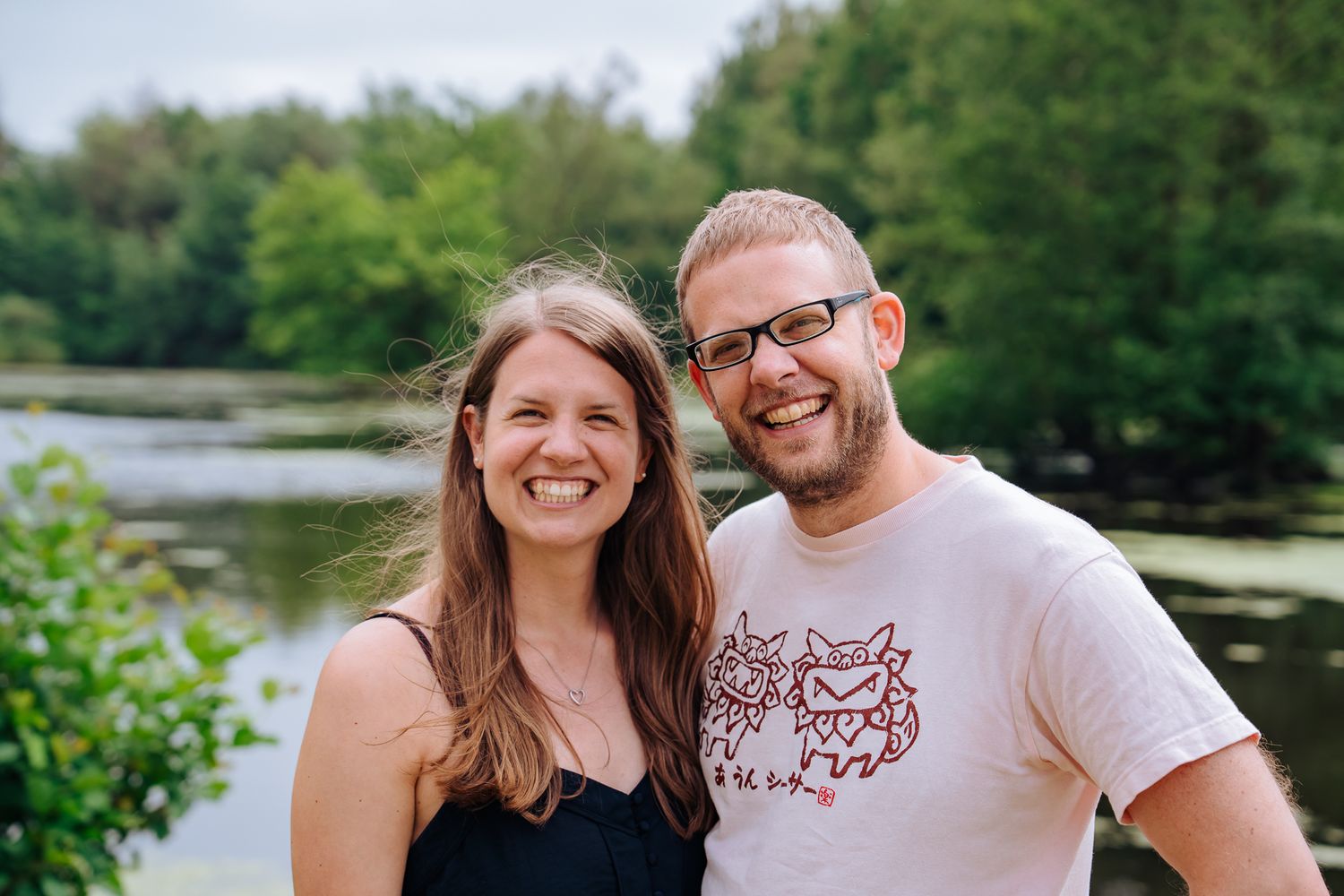 Geschwisterpaar lächelt gemeinsam und umarmt sich, im Hintergrund ist der Lütjensee zu sehen