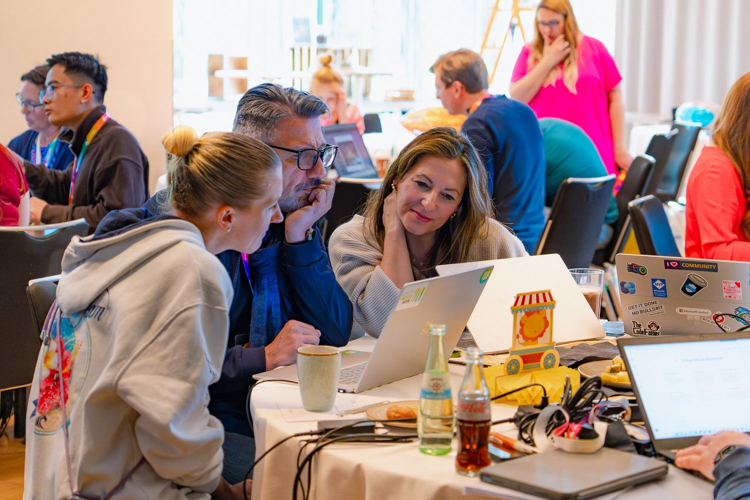 Drei Teilnehmende an dem ColorCloud PromptAthon arbeiten gemeinsam vor ihren Laptop