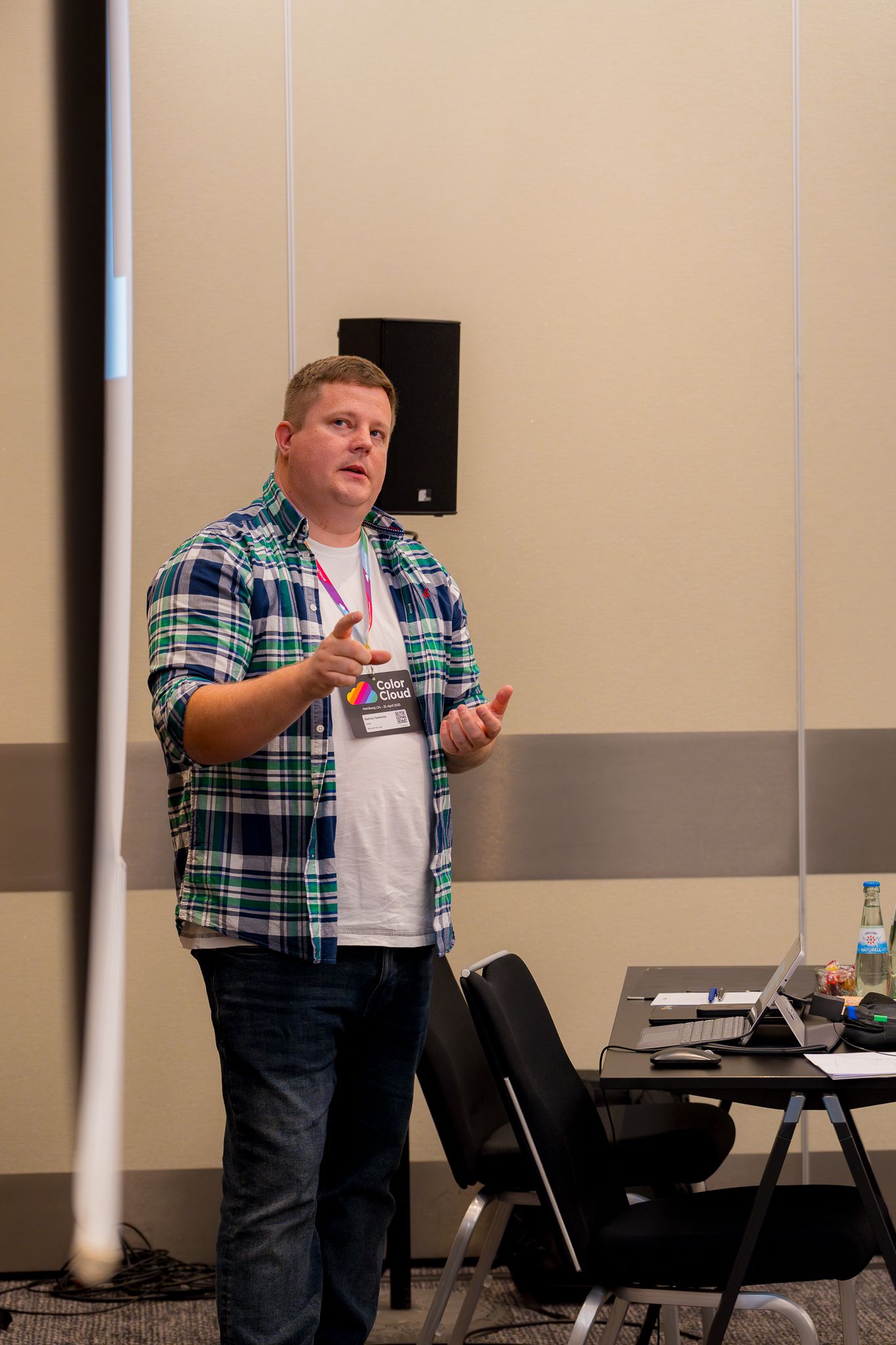 Nathan Sweeney zeigt auf eine Leinwand während er vor Teilnehmenden an der ColorCloud-Konferenz einen Vortrag hält
