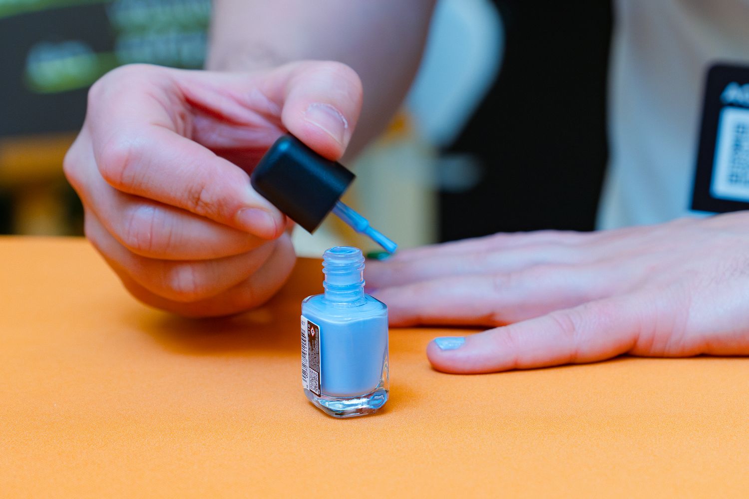 Ein Teilnehmer bemalt die Fingernägel seiner linken Hand mit blauem Nagellack