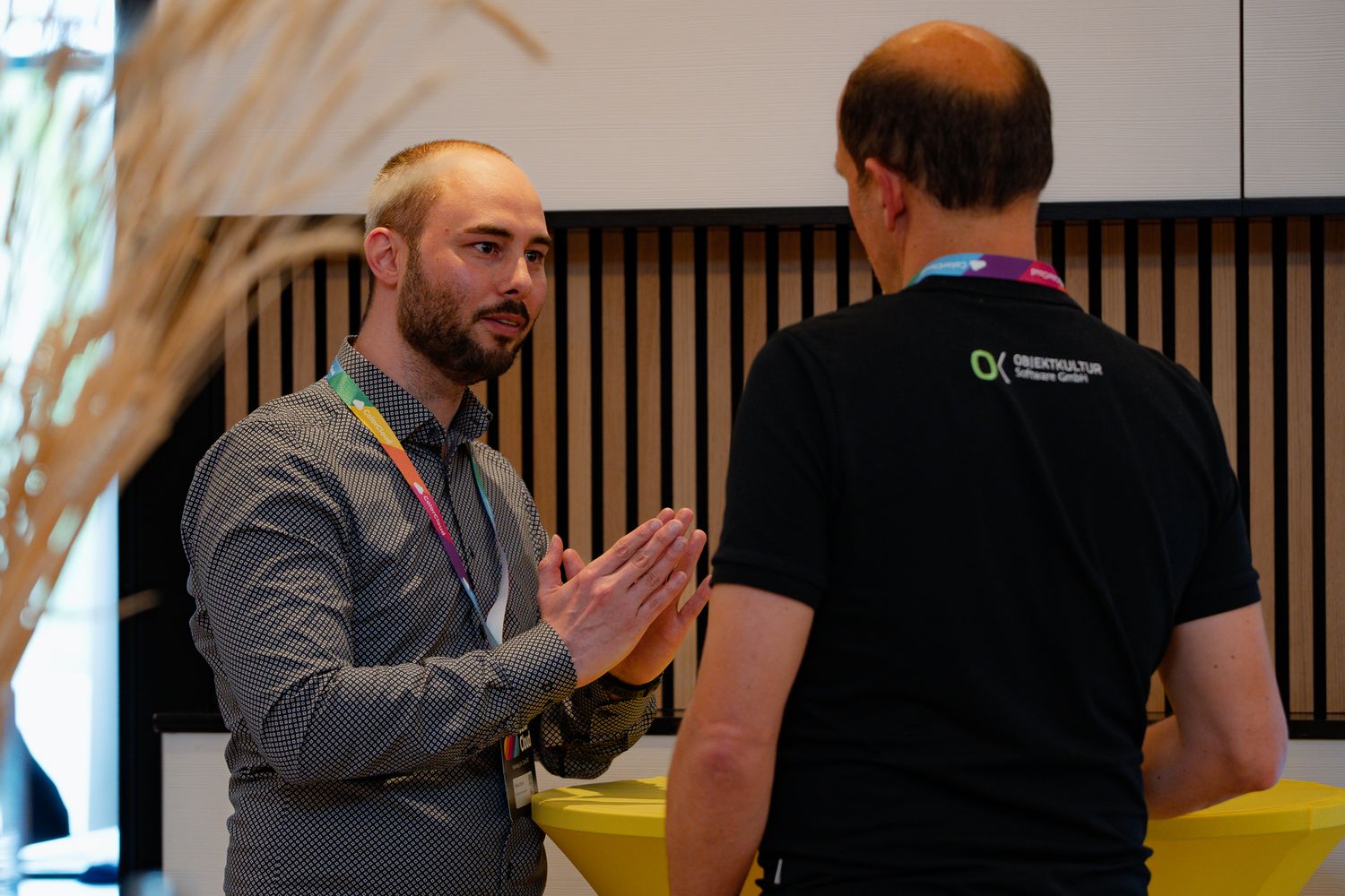 Zwei Teilnehmer der ColorCloud-Konferenz unterhalten sich an einem gelben Stehtisch im Foyer