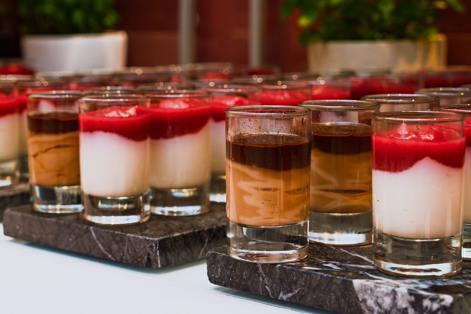 Desserts in kleinen Gläsern mit heller Creme und Fruchtspiegel auf dem Buffet