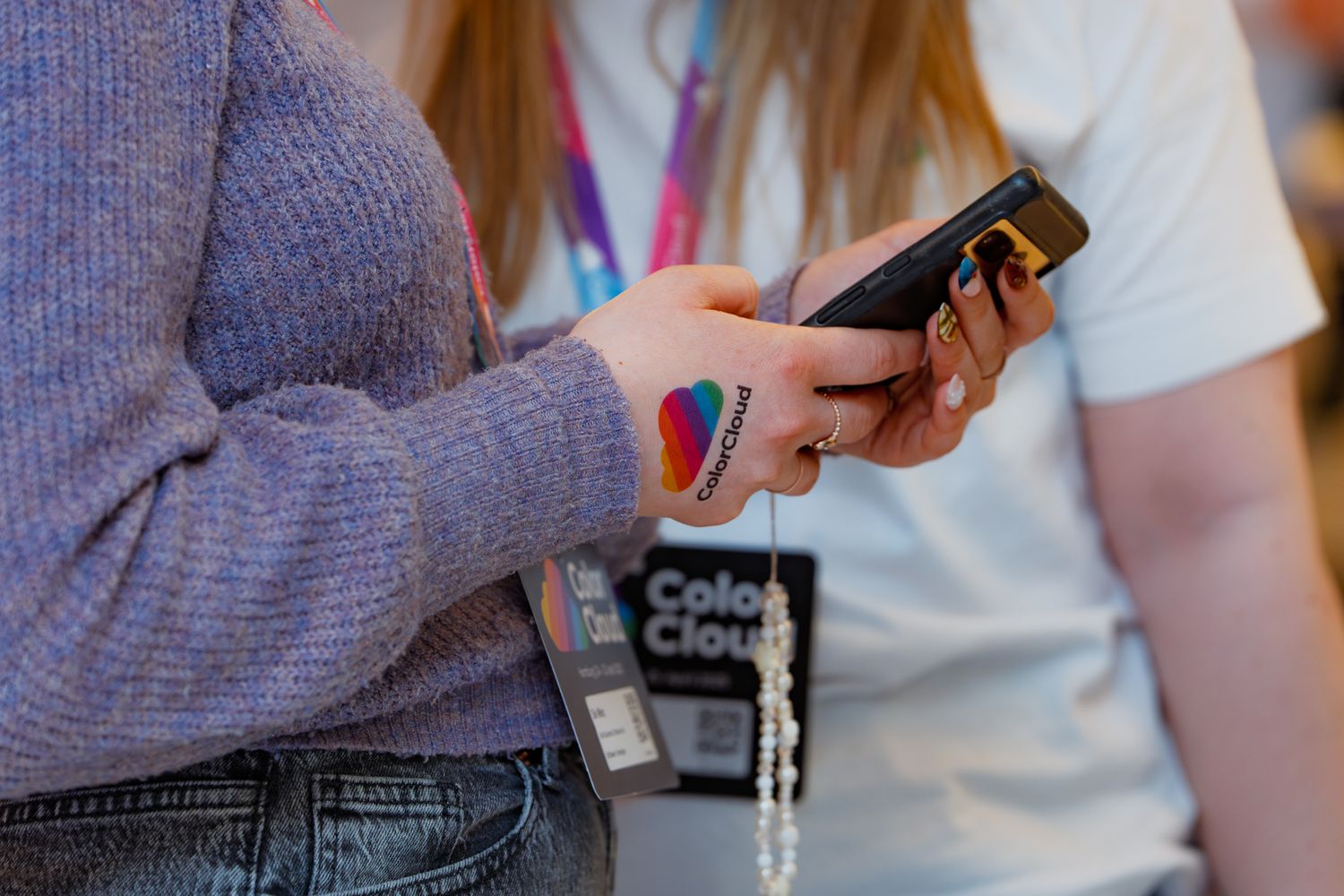 Eine Teilnehmerin mit einem bunten ColorCloud-Tattoo auf dem Handrücken sucht nach Informationen auf ihrem Smartphone