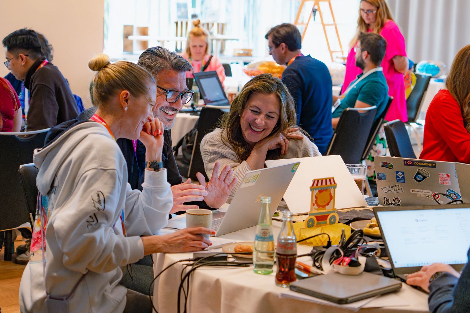 Zwei Frauen und ein Mann arbeiten während des Workshops gemeinsam an einem Laptop und lachen über etwas auf dem Bildschirm