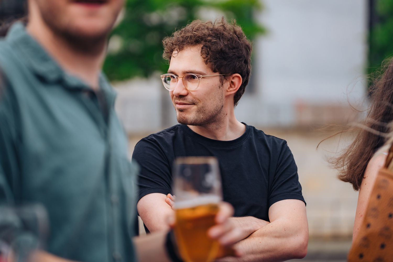 Junger Mann mit schwarzen T-Shirt und Brille mit verschränkten Armen