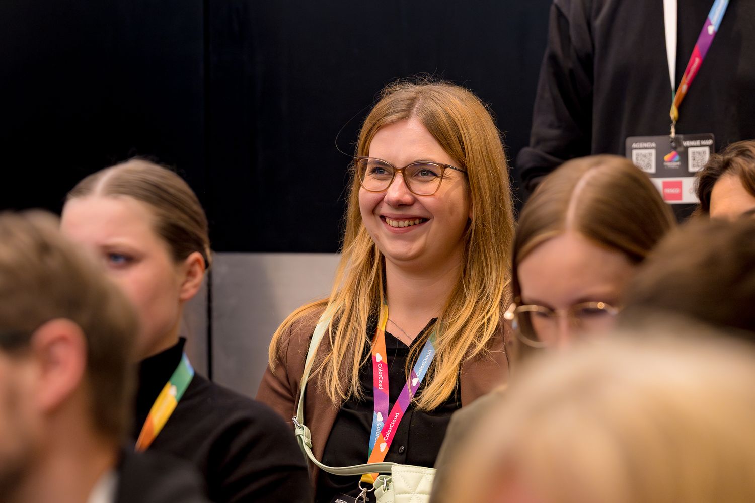Eine Frau mit Brille im Publikum schaut lachend nach vorne zum Speaker