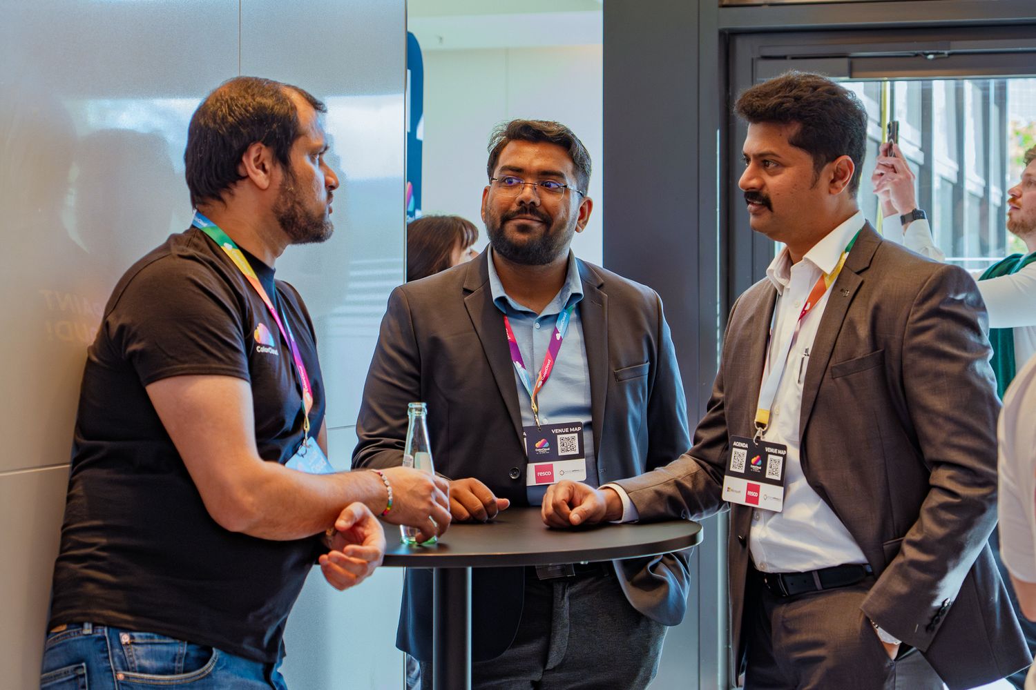 Drei Männer stehen am Stehtisch im Foyer der ColorCloud-Konferenz und unterhalten sich