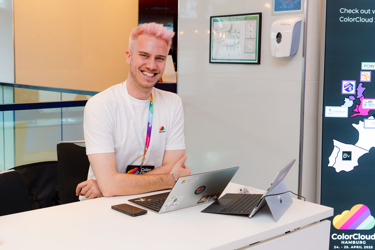 Mats Necker, Gründer der ColourCloud-Konferenz, sitzt am Empfangstisch und wartet auf die Teilnehmenden