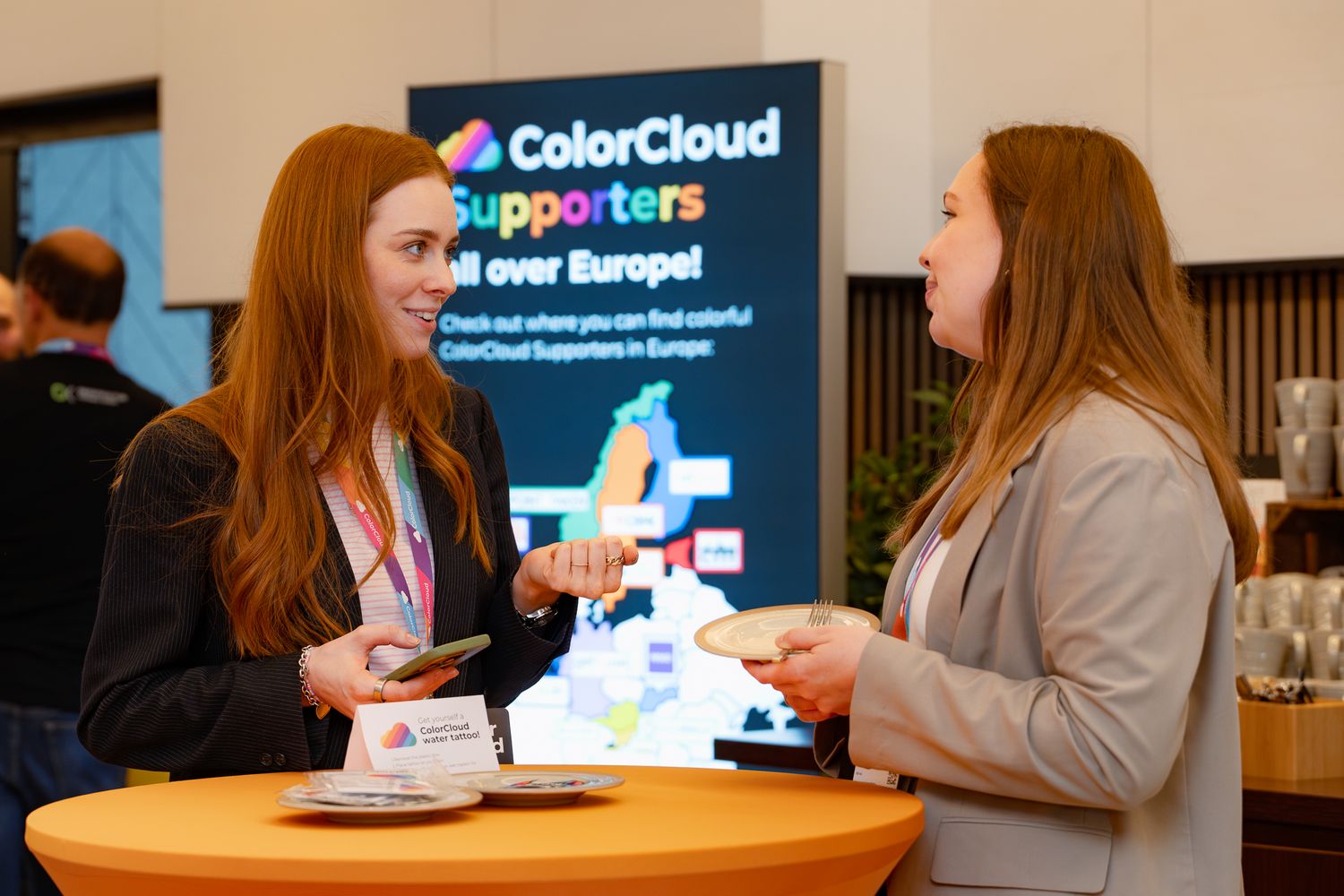 Zwei Teilnehmerinnen an der ColorCloud Konferenz unterhalten sich an einem Stehtisch im Foyer
