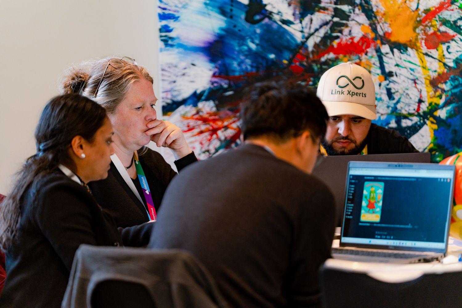 Eine Gruppe von Teilnehmenden am ColorCloud PromptAthon arbeiten konzentriert an ihren Laptops