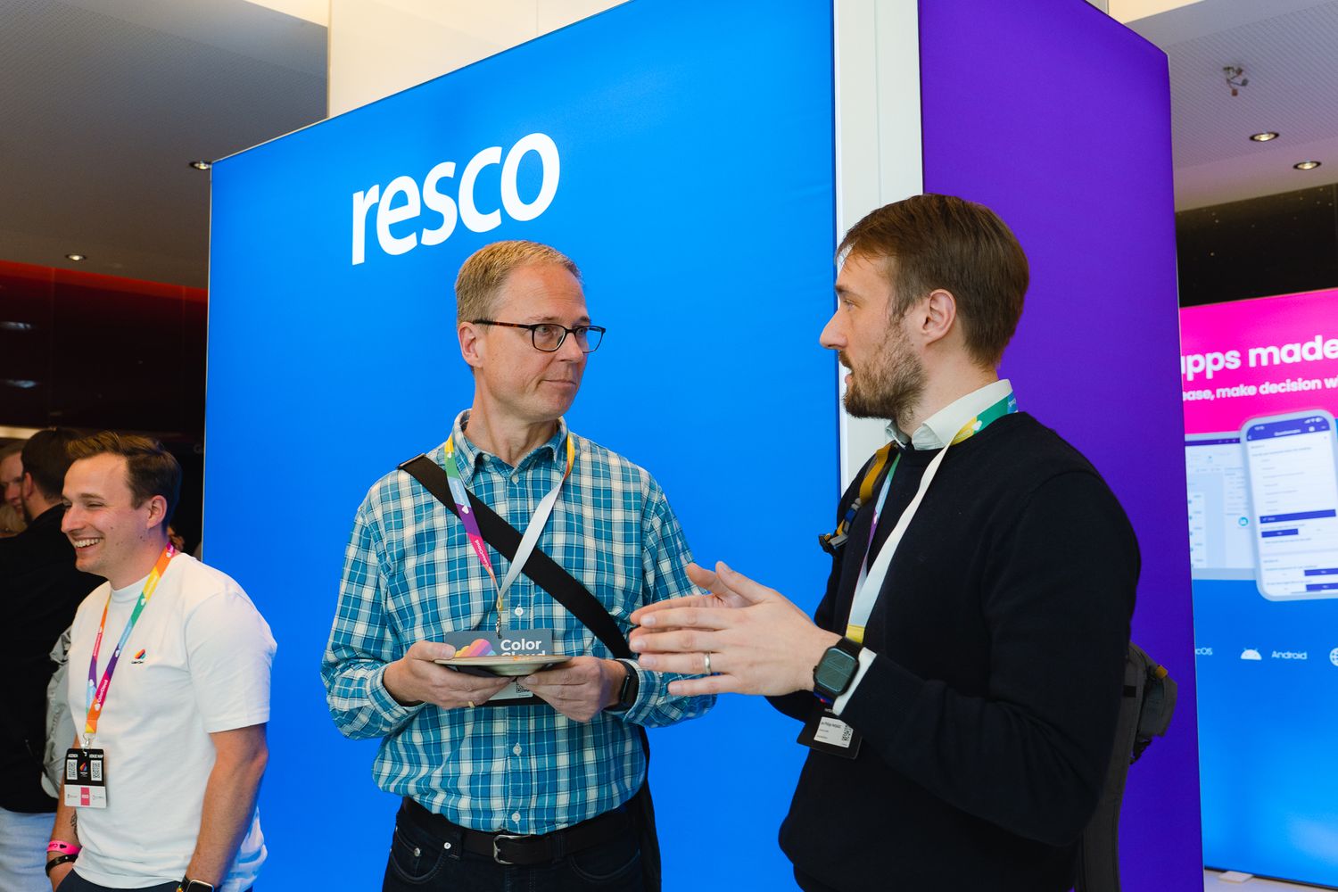 Zwei Teilnehmende an der ColorCloud-Konferenz unterhalten sich am Sponsorenstand von Resco