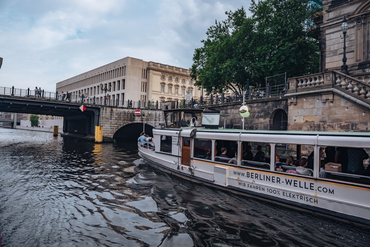 Ausflugsschiff ‚Berliner Welle‘ auf der Spree unterhalb einer Brücke mit Fußgängern