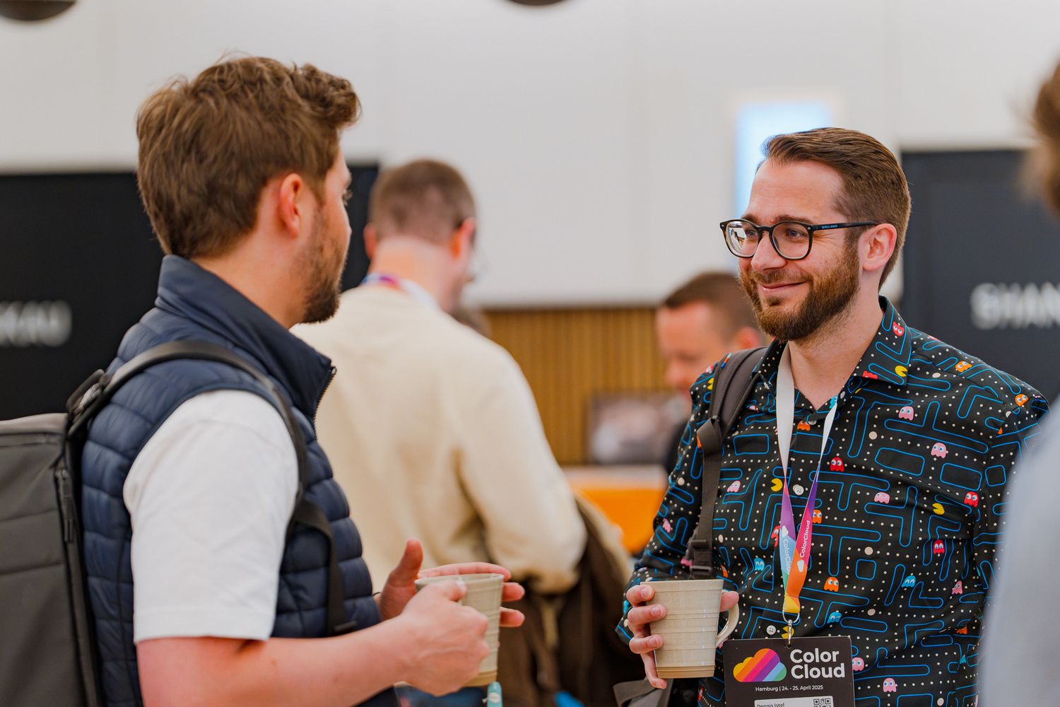 Zwei Teilnehmende der ColorCloud-Konferenz unterhalten sich und halten Kaffeetassen in der Hand
