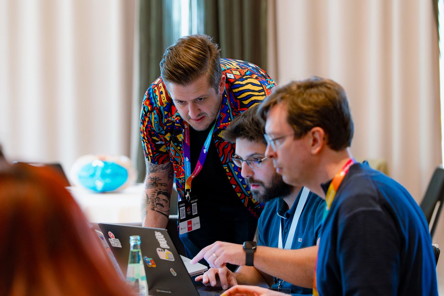 Zwei Teilnehmer des ColorCloud-Promptahon gucken gemeinsam mit William Dorrington auf einen Laptop-Bildschirm