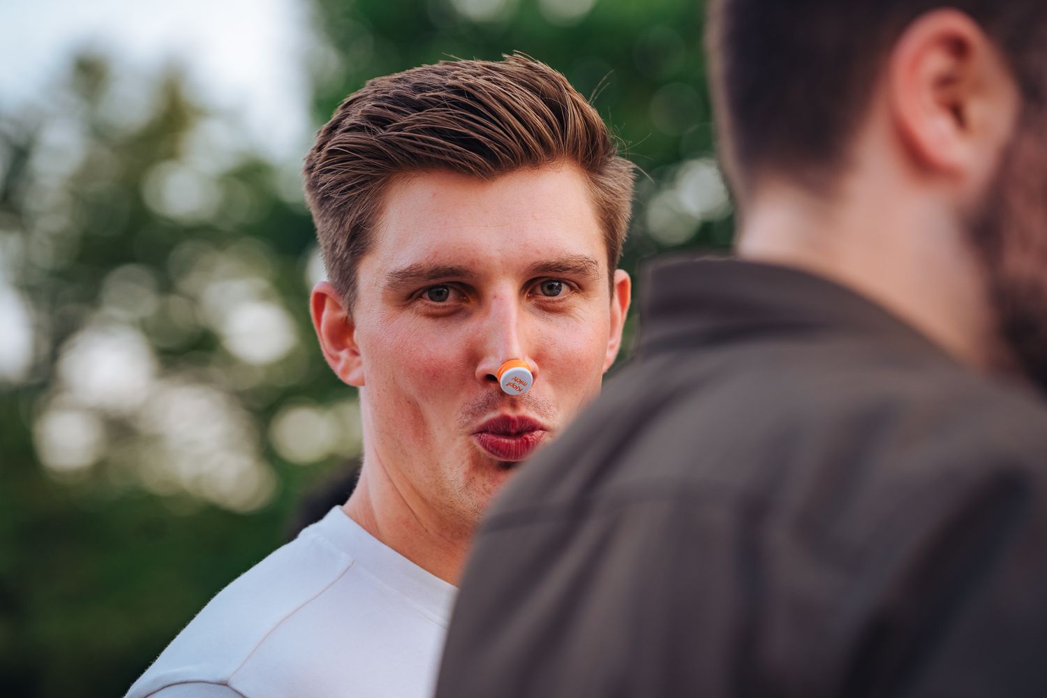 Junger Mann mit Flaschendeckel auf der Nase