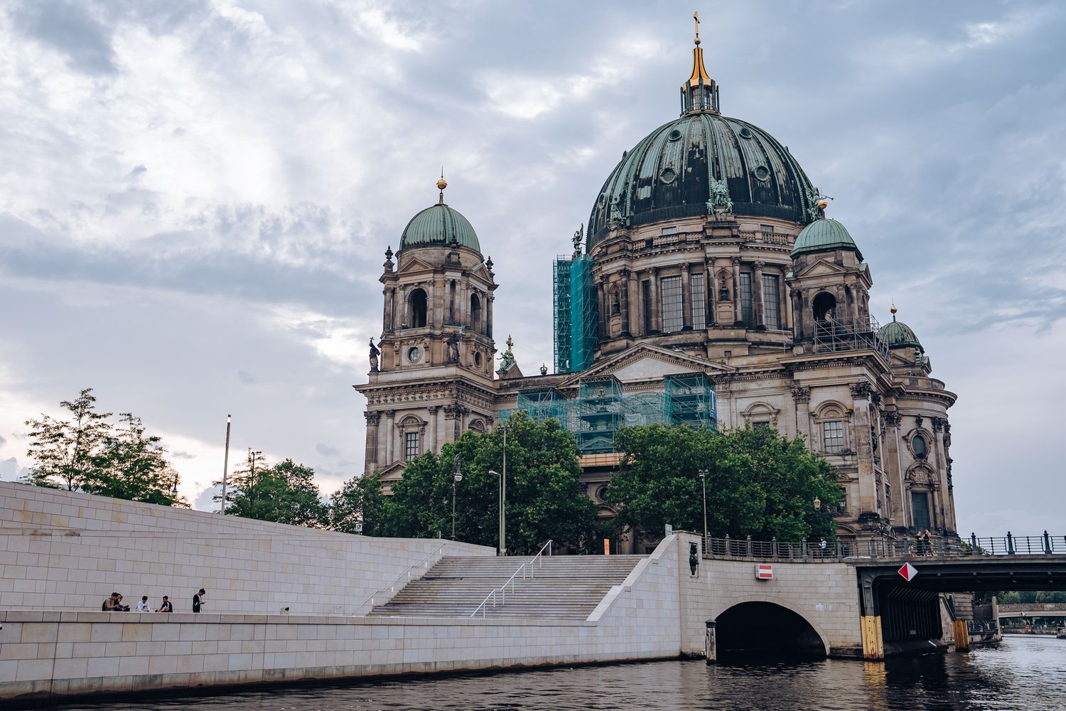 Berliner Dom mit Restaurierungsarbeiten an der Fassade, breite Treppe und Bäume im Vordergrund