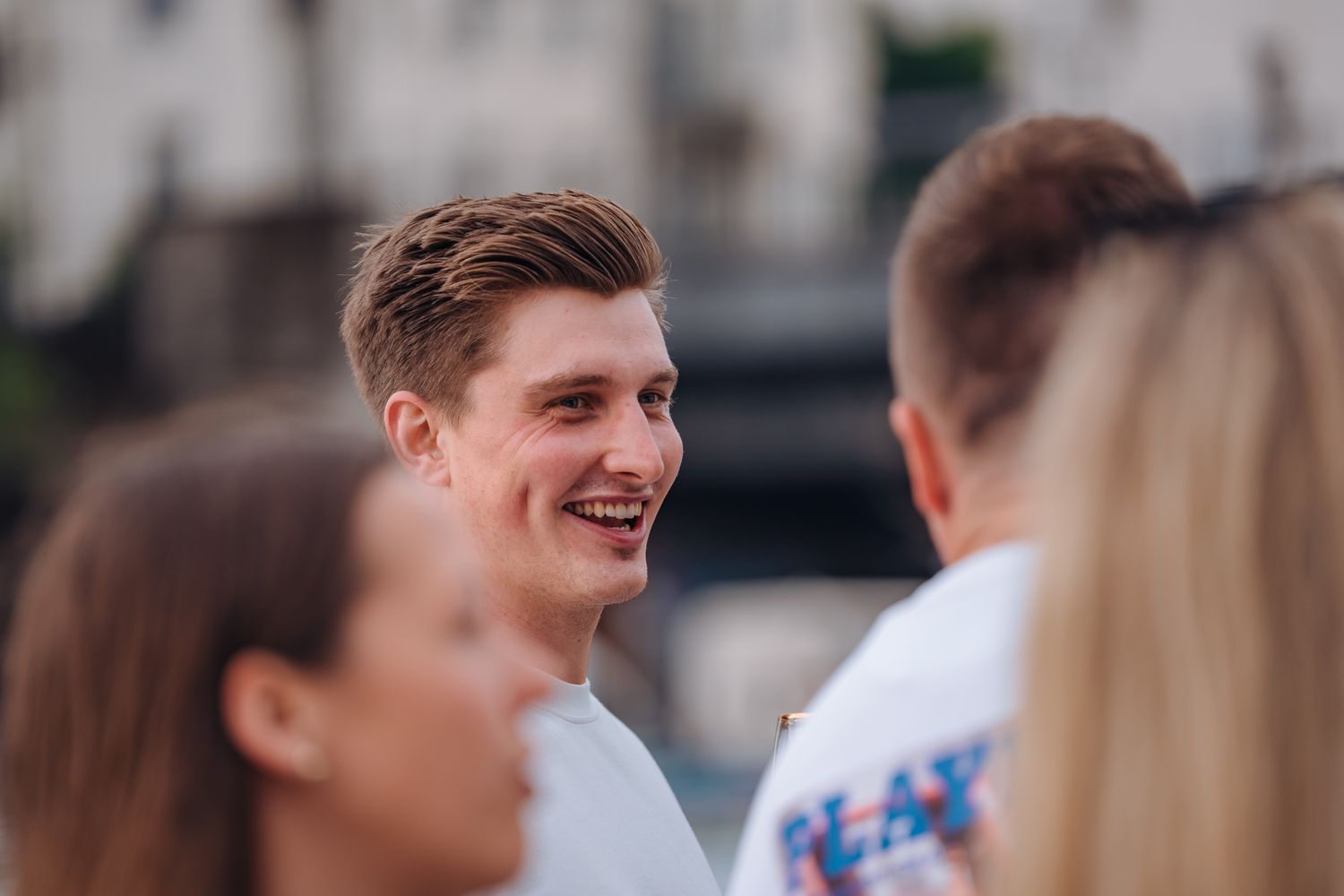 Lachender junger Mann mit blonden Haaren im weißen T-Shirt