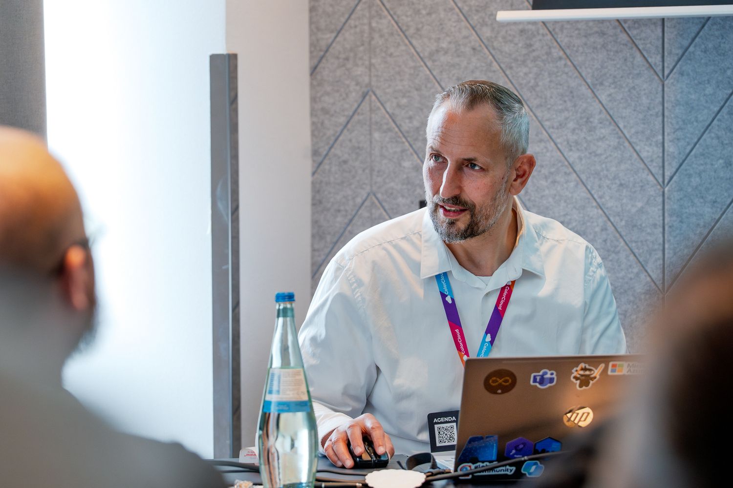 Michael Megel sitzt vor einem Laptop und hält vor Teilnehmenden auf der ColorCloud-Konferenz 2025 einen Vortrag