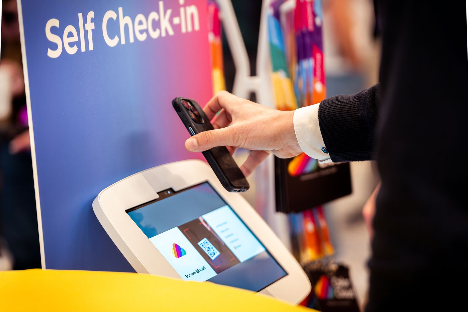 Teilnehmer an der ColorCloud 2025 in Hamburg scannt sein Smartphone am Self-Check-in-Terminal