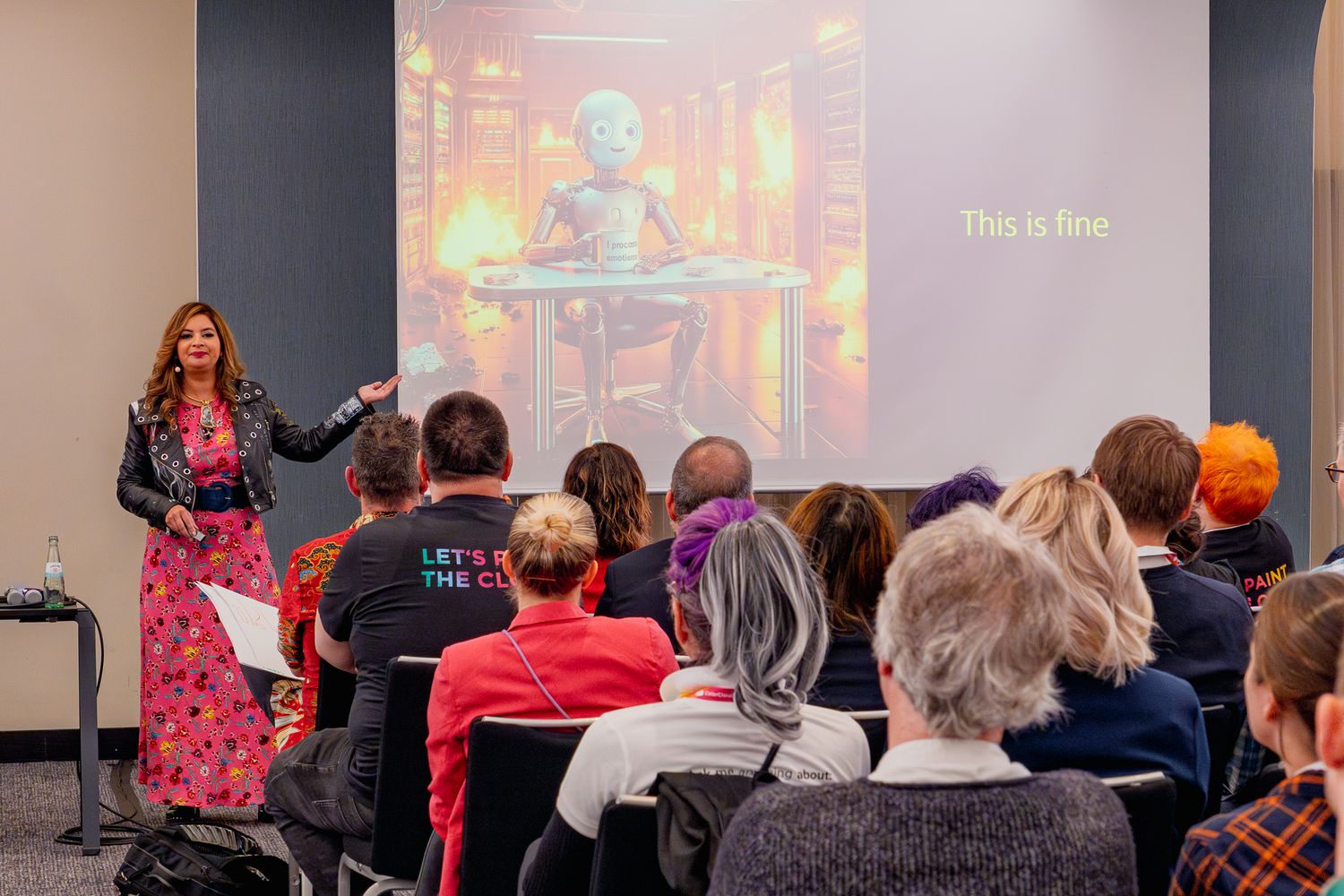 Dona Sarkar hält die Keynote auf der ColorCloud 2025, im Hintergrund ist ein Roboter auf einer Leinwand, der von Flammen umgeben ist