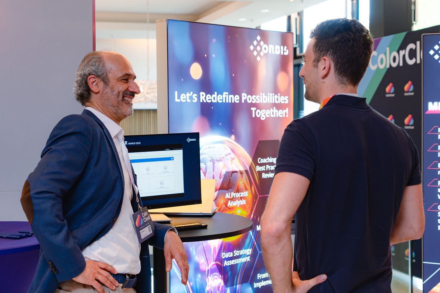 Zwei Personen unterhalten sich am Sponsorenstand von Orbis auf der ColorCloud 2025