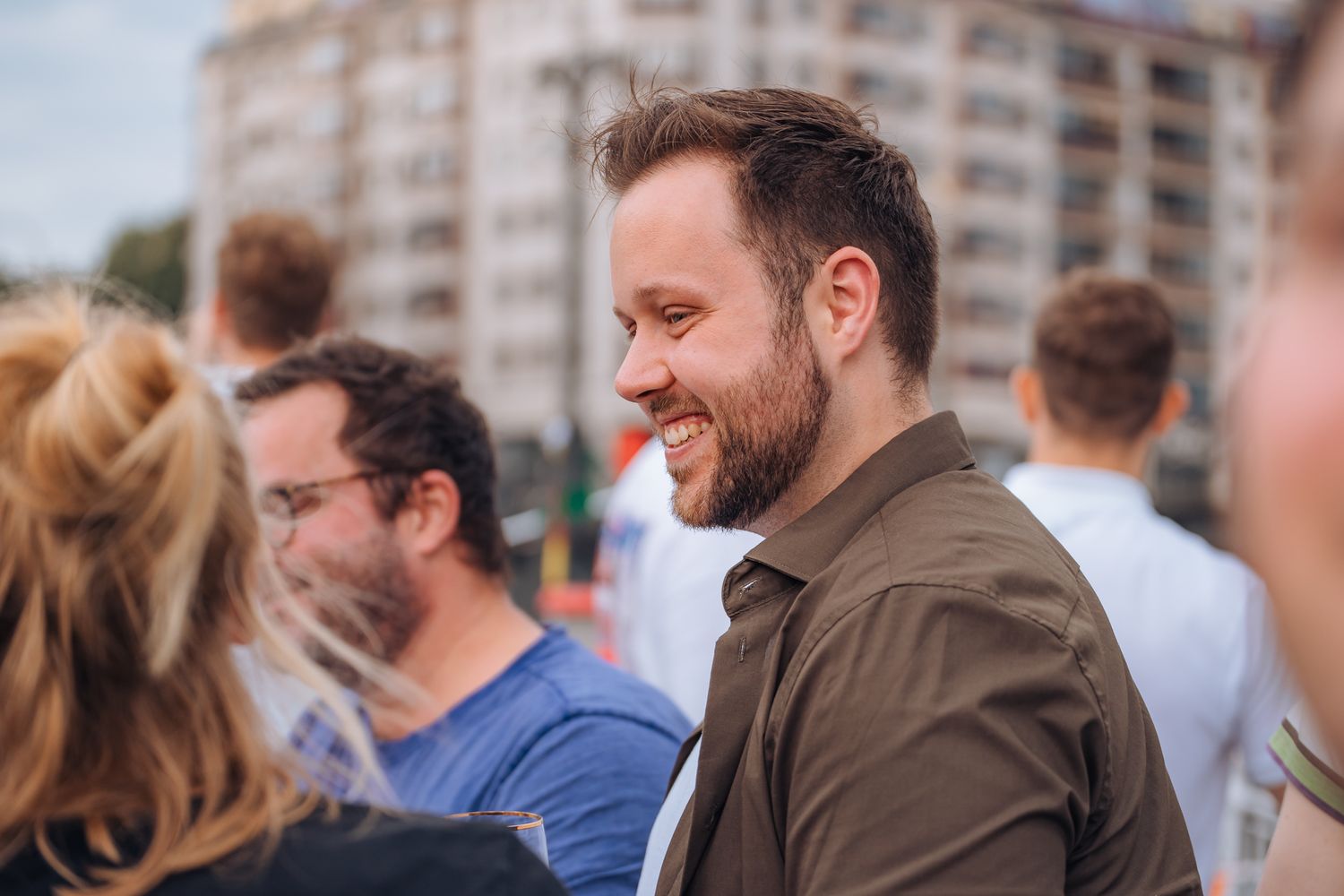 Junger lachender Mann mit. braunen kurzen Haaren und khakifarbenem Hemd