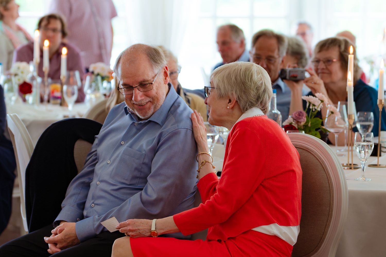 Das Geburtstagspaar und die feiernden Gäste hören der Rede zu