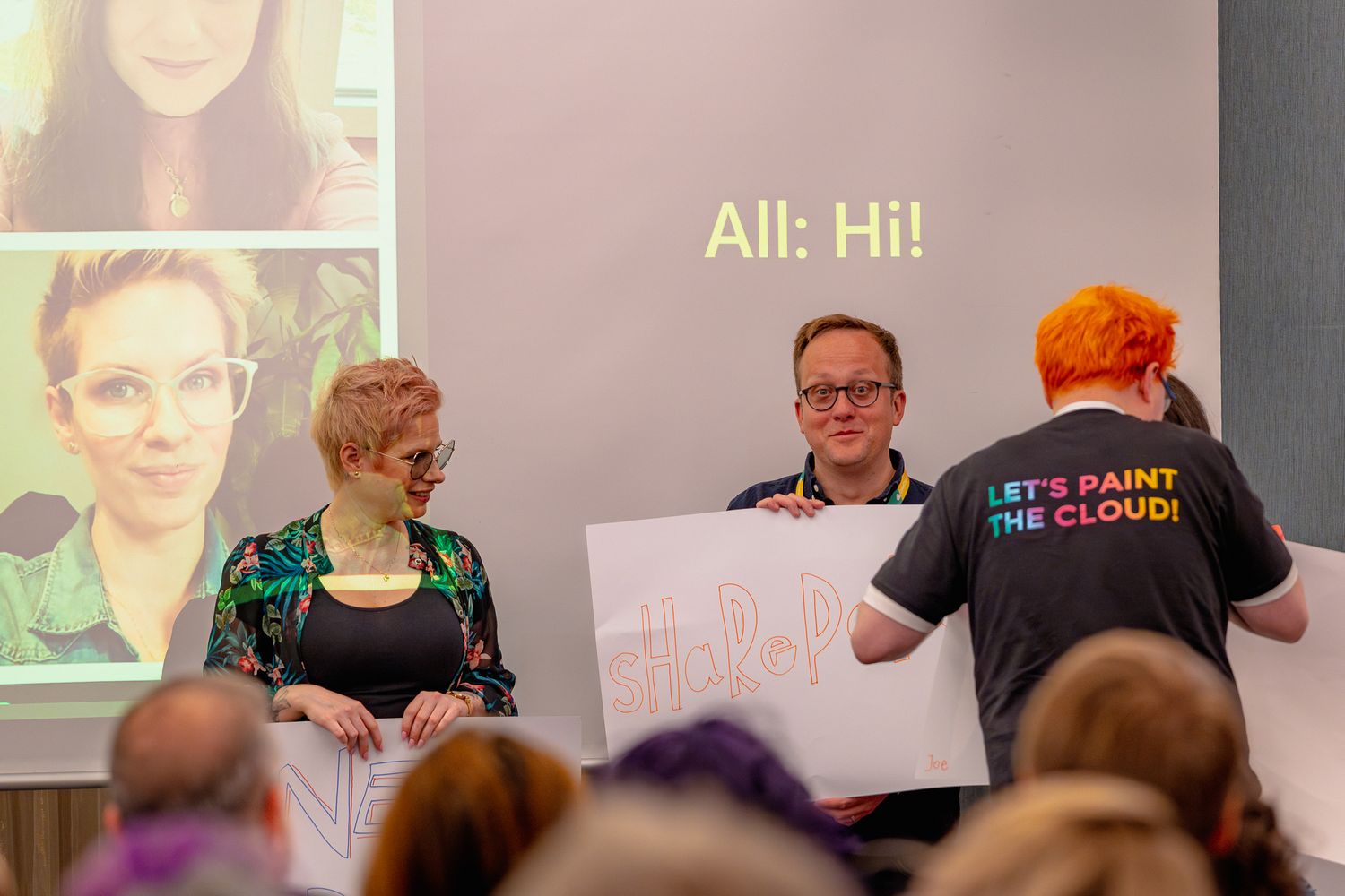 Drei Keynote-Speaker halten weiße Schilder hoch und sprechen zum Publikum der Eröffnungsrede der ColorCloud