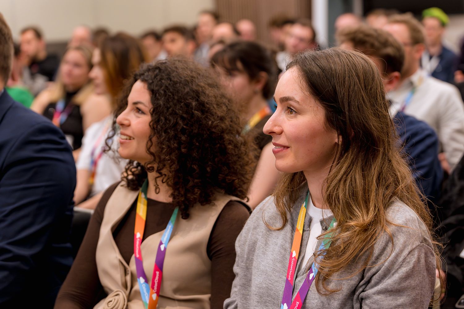 Zwei Frauen aus dem Publikum hören lächelnd einem Vortrag auf der ColorCloud-Konferenz 2025 zu